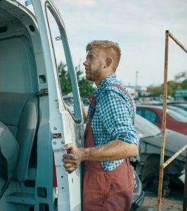 Male repairman removes the door on car scrapyard